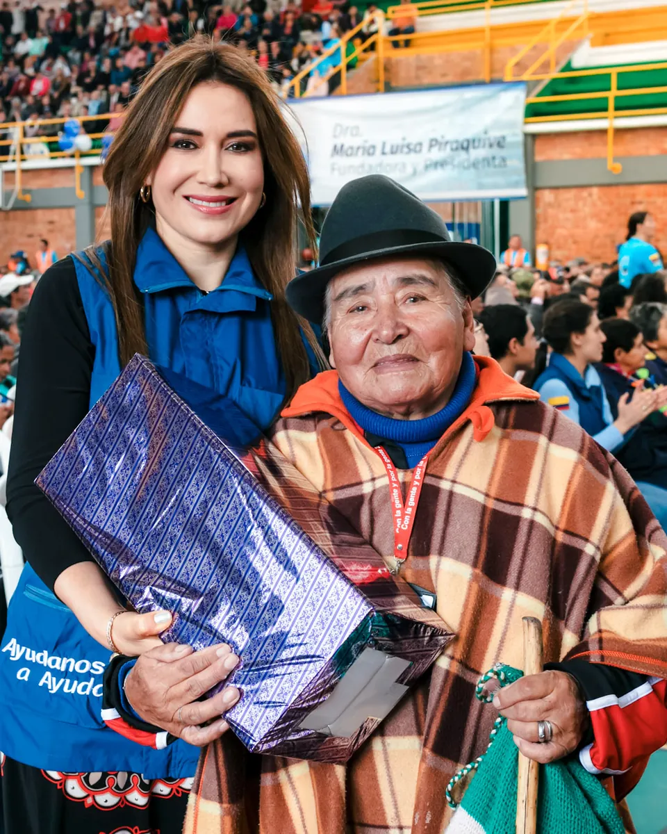 La Dra. Ángela Oviedo con una persona mayor que sostiene un regalo en un evento de la Fundación