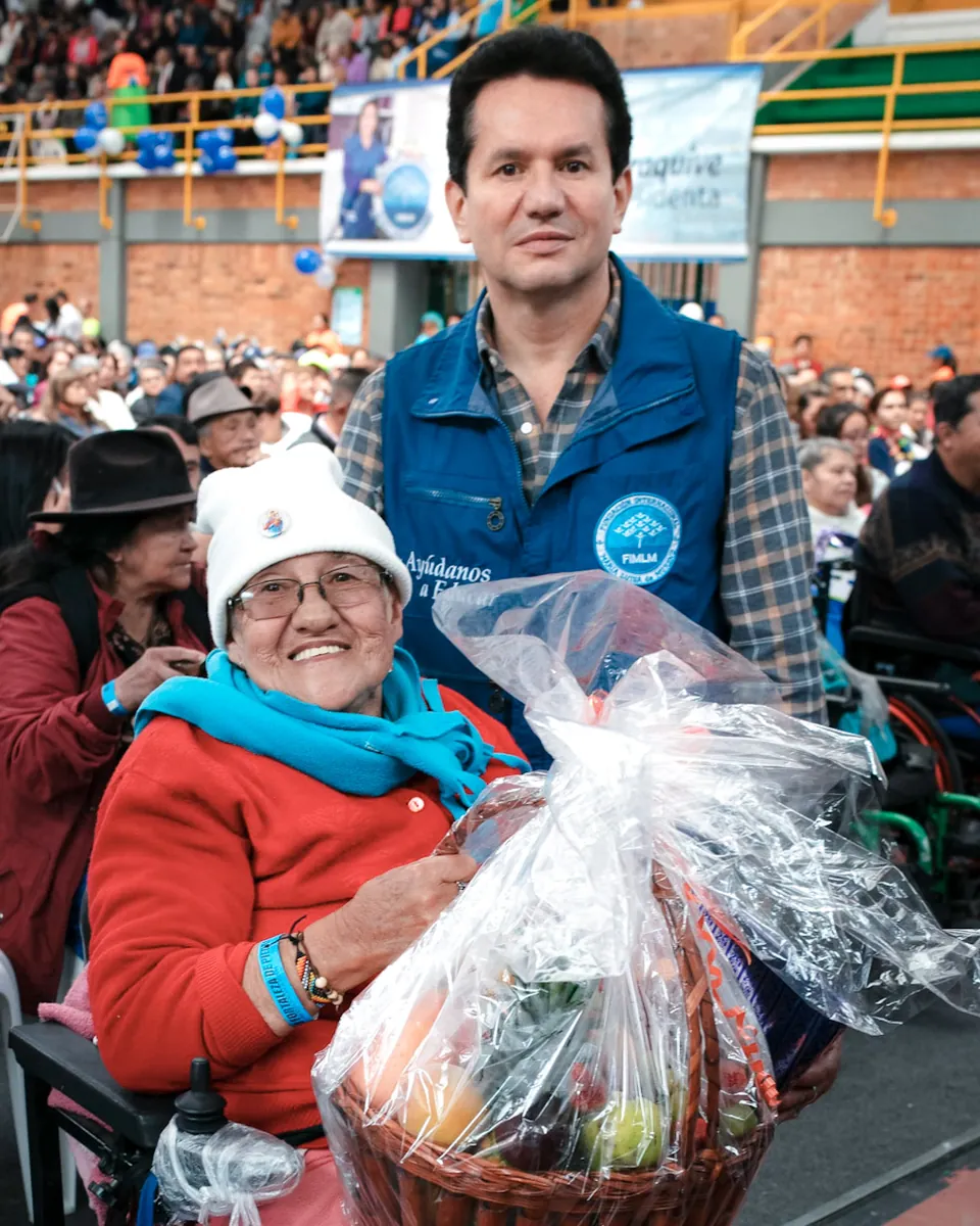 El Dr. César Eduardo Moreno con un beneficiario que sostiene una canasta de regalo en un evento de la Fundación
